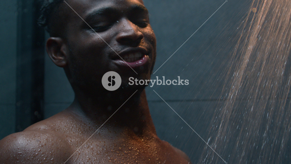 Close up happy African American man take shower singing favorite song enjoying morning hygiene body refreshing listen music in bathroom