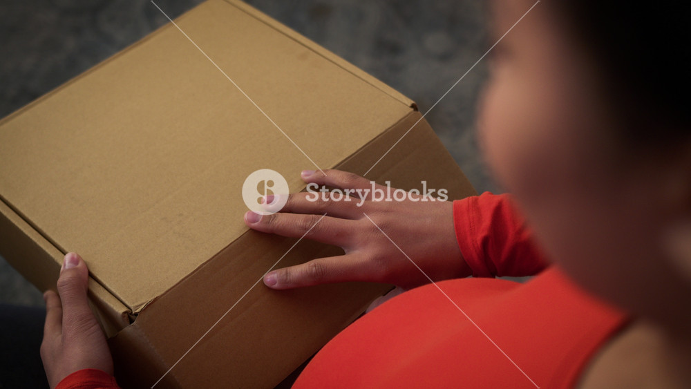 African American girl pregnant woman mother female lady pregnancy child anticipation at home couch unpacking parcel delivered box with kid