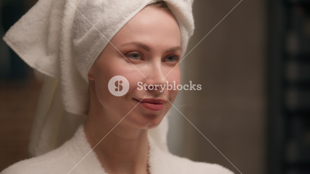 Beautiful young woman girl applying cooling hydrogel eye patches skincare bath Caucasian female model wearing bath towel bathrobe beauty