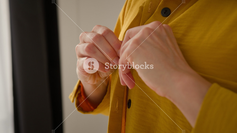 Hands close up Caucasian woman girl female influencer wear buttoning up yellow shirt clothes blogger lady prepare to work getting ready to