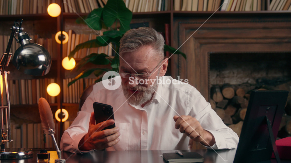Caucasian old retired business man waiting result yelling winning with mobile phone at office emotional senior aged elderly businessman male