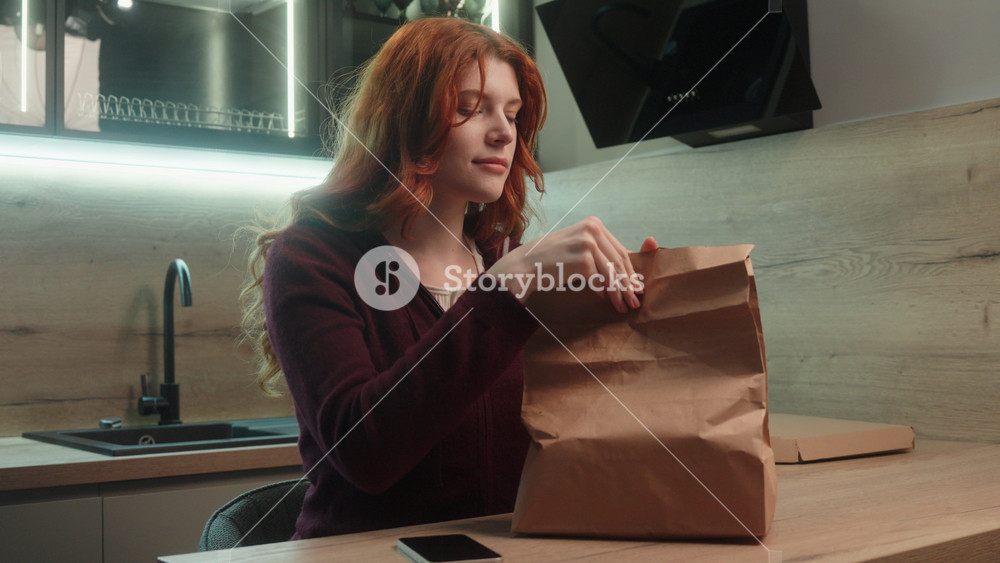 Caucasian woman unpacking paper bag with food delivery order sniffing tasty aroma enjoying good smell happy female girl with craft package