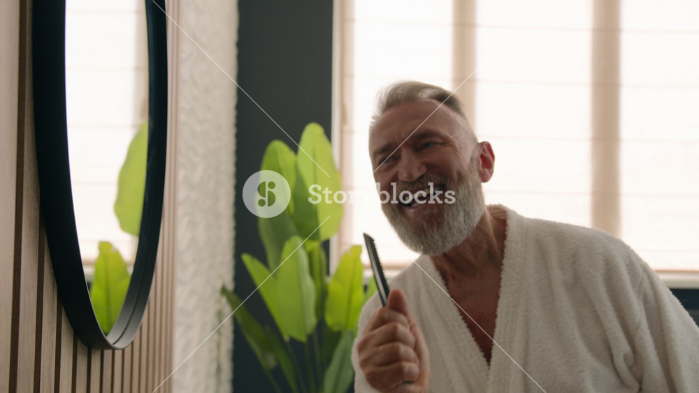 Funny Caucasian old middle-aged retired elderly male senior mature man humorous silly carefree singing in hair brush sing song in hairbrush