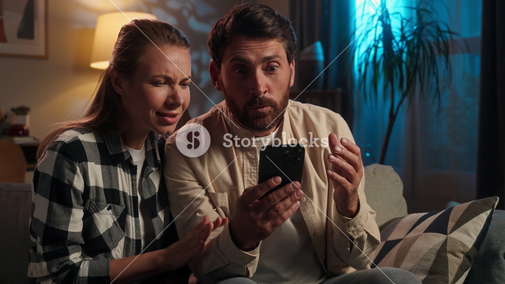 Happy Caucasian middle-aged winning with mobile phone victory online with smartphone family yelling adult spouses woman man husband wife win