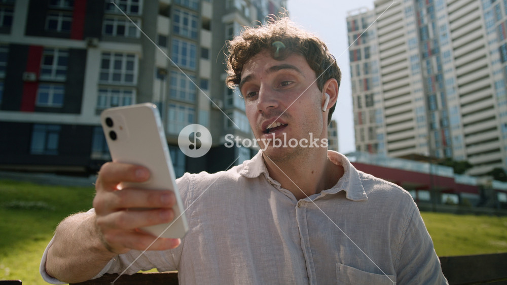 Caucasian man using mobile phone smartphone online meeting greeting waving headphones city male guy businessman blogger communication