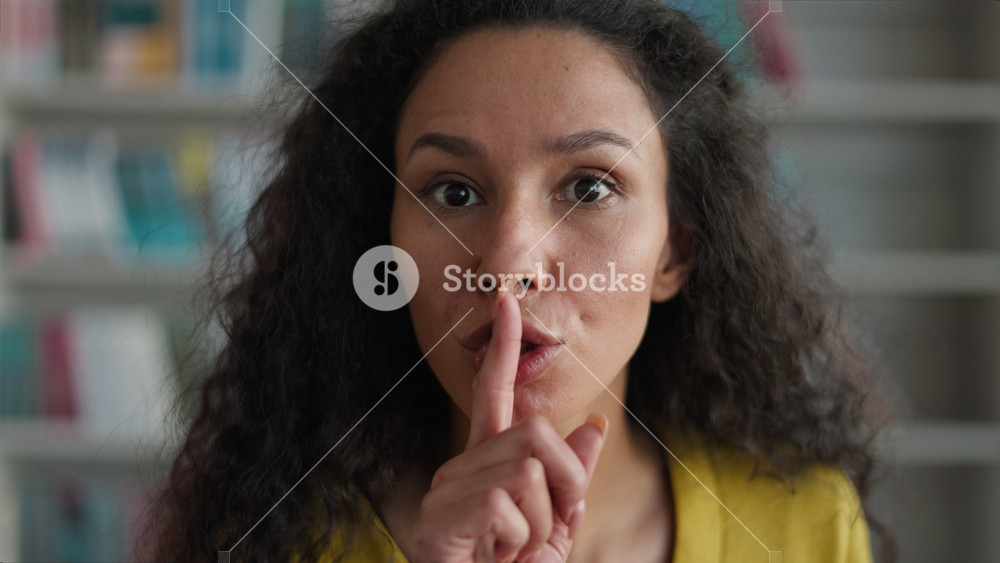 Latino Arabian Indian Hispanic woman silence sign holding finger mouth quiet gesture hush forbids speak secret female library girl student