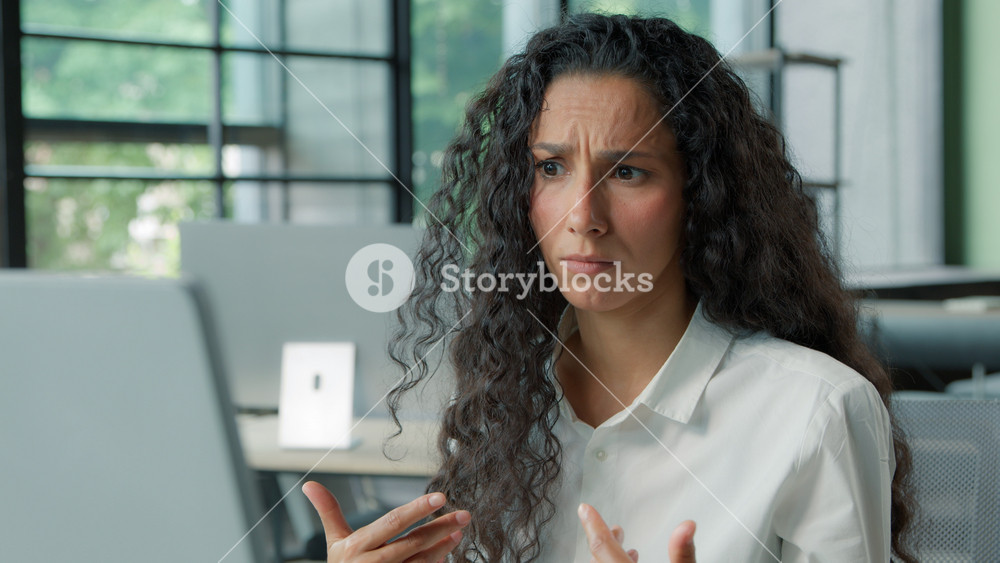 Close-up confused Hispanic business woman looking at camera shrug shoulders with computer businesswoman puzzled reading bad news email