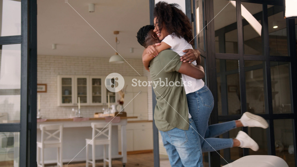 African American love couple happy family meeting at home woman jumping man hugging spinning together laugh affection embrace cuddle