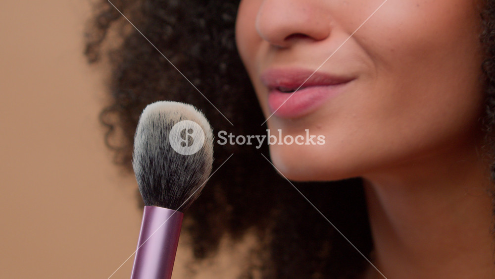 Cosmetic make-up beauty concept close-up cropped view unrecognizable African American woman unknown model girl holding brush blow away dust