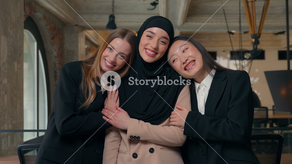 Three happy smiling friendly multiracial business women friends diversity businesswomen girls females hugging cuddling support Muslim girl