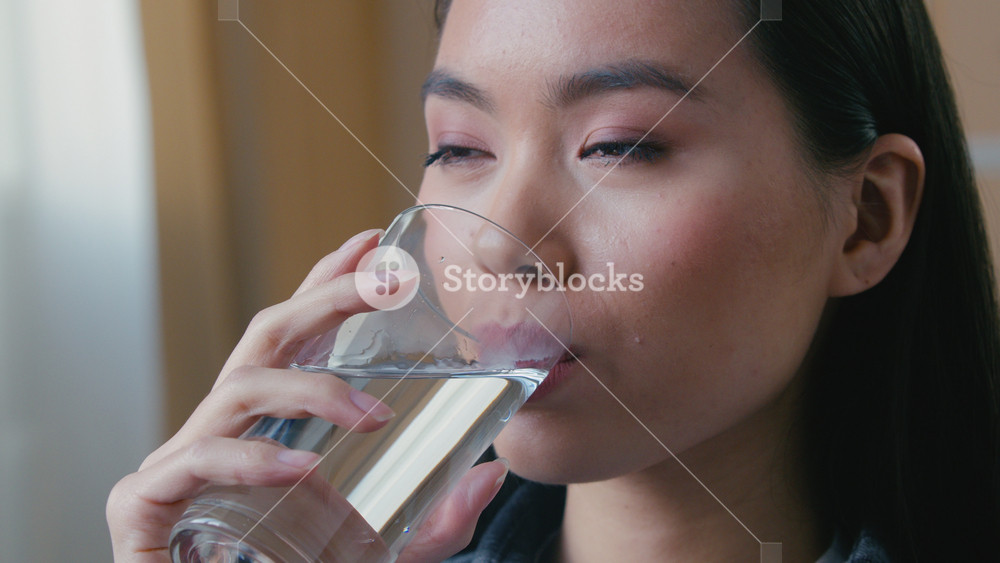 Close up Asian Korean woman drinking clean water at home morning hydration ritual smiling female Japanese girl holding glass healthy