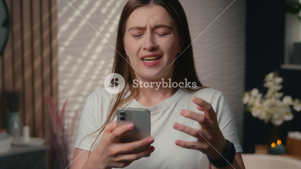 Stressed worried sad Caucasian woman girl displeased upset lady user smartphone addict female looking cellphone screen in home bathroom bad