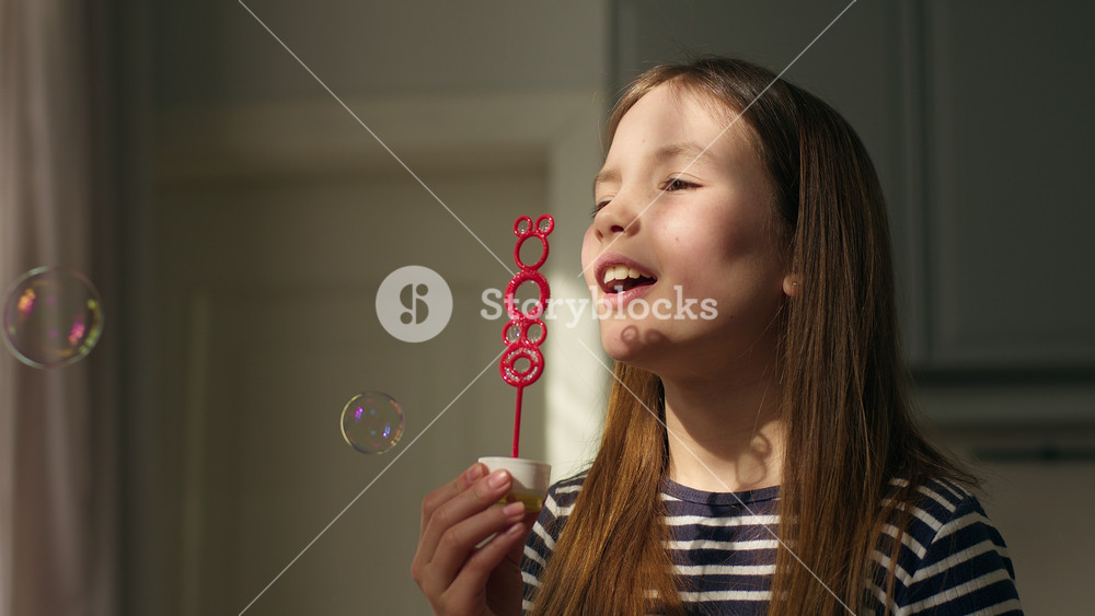 Caucasian European little girl blowing soap bubbles daughter child childhood fun enjoyment smile happy female play time kid baby bubble