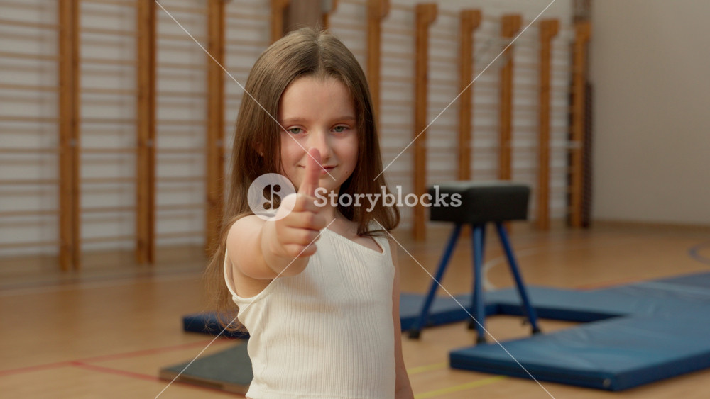 Caucasian little girl good gesture showing thumb up schoolgirl kid finger raise school smile teenage recommend education sport gym child