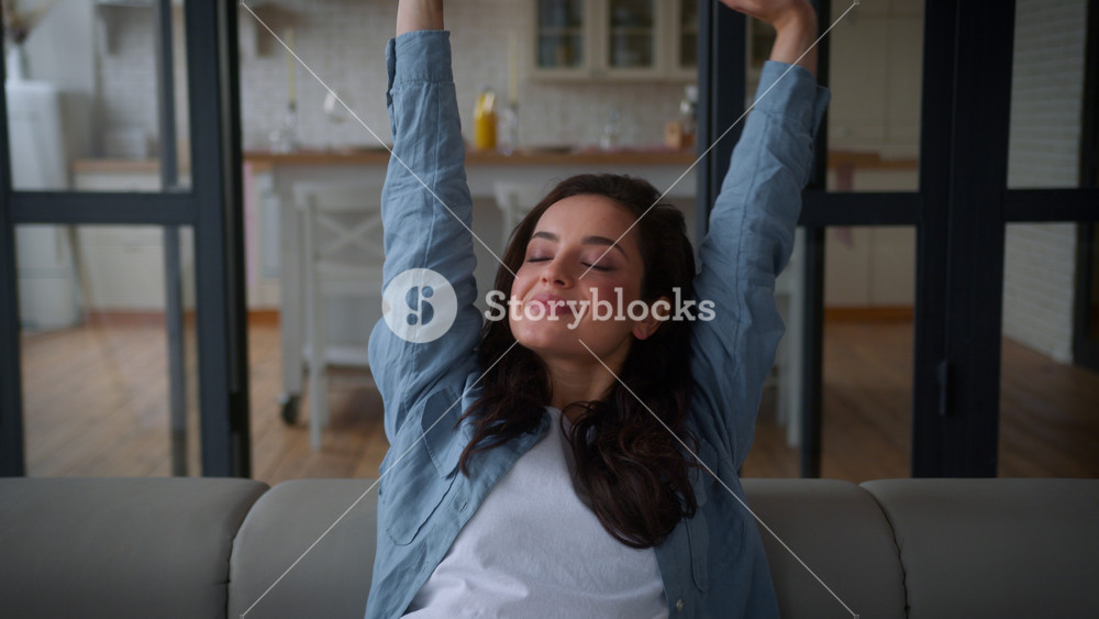 Happy Caucasian girl female woman relax on cozy couch enjoying lazy weekend at own home loan mortgage insurance apartment smiling raising