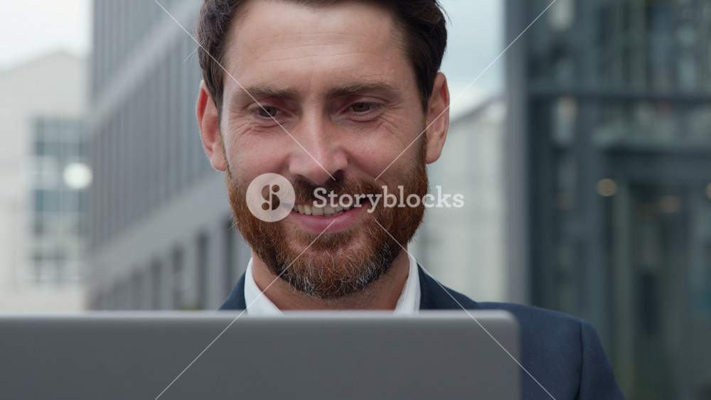 Close-up smiling handsome mature Caucasian business man looking at laptop in city smile toothy happy businessman male look at computer