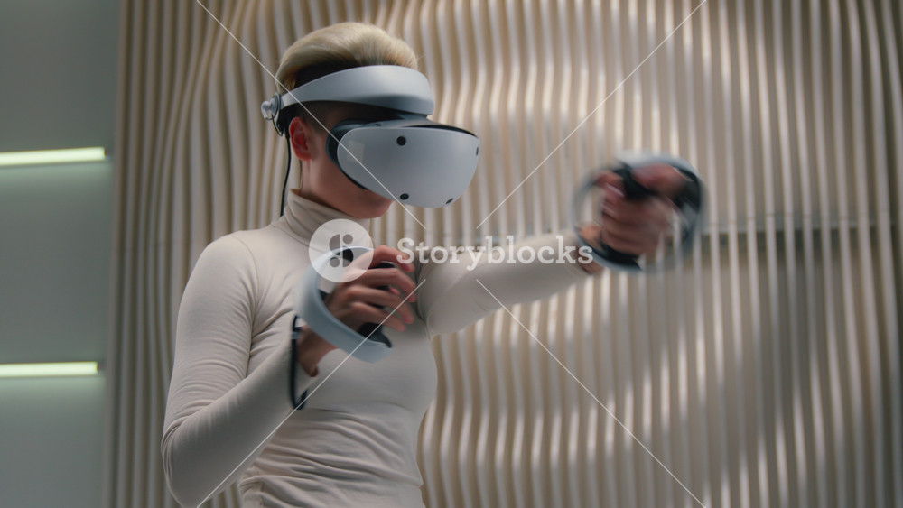 White futuristic space Caucasian woman female girl in VR glasses helmet 3d playing pretend kick hologram hold joystick kicking in air gaming