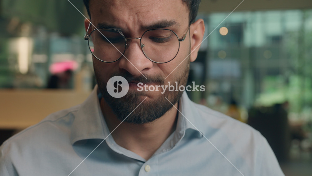 Angry sad Indian man Arabian male business guy employee worker manager mad frustrated worried businessman in cafe stressed problem earphones