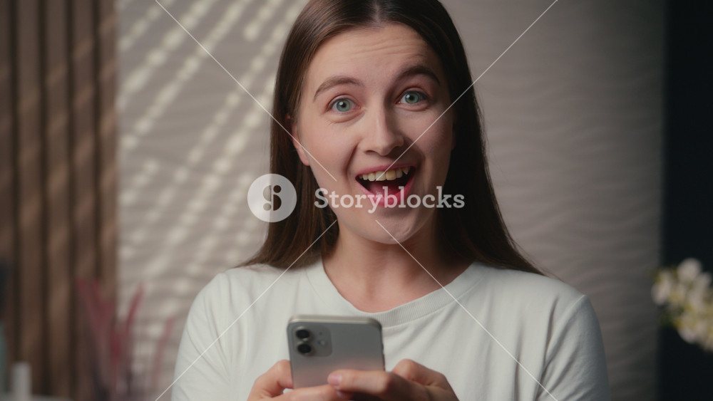 Surprised happy Caucasian woman girl in home bathroom reading message cellphone shock wow amazement wonder achieve good result online