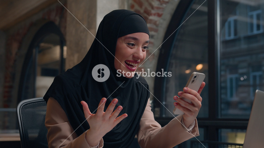 Arabian islamic girl muslim woman in hijab amazed happy joyful female businesswoman read good news smartphone win victory business