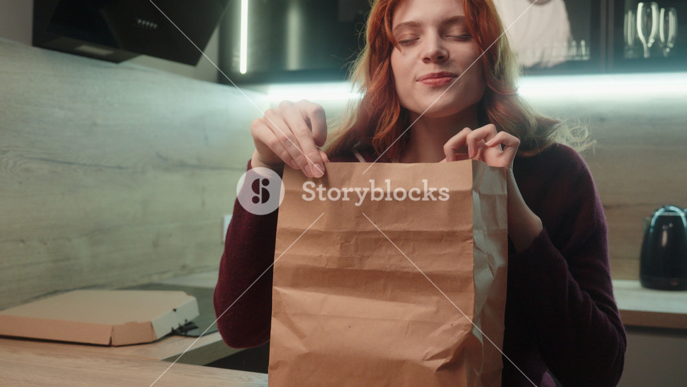Happy smiling young Caucasian woman female girl client customer unpacking open paper bag order package fast food lunch opening snack meal