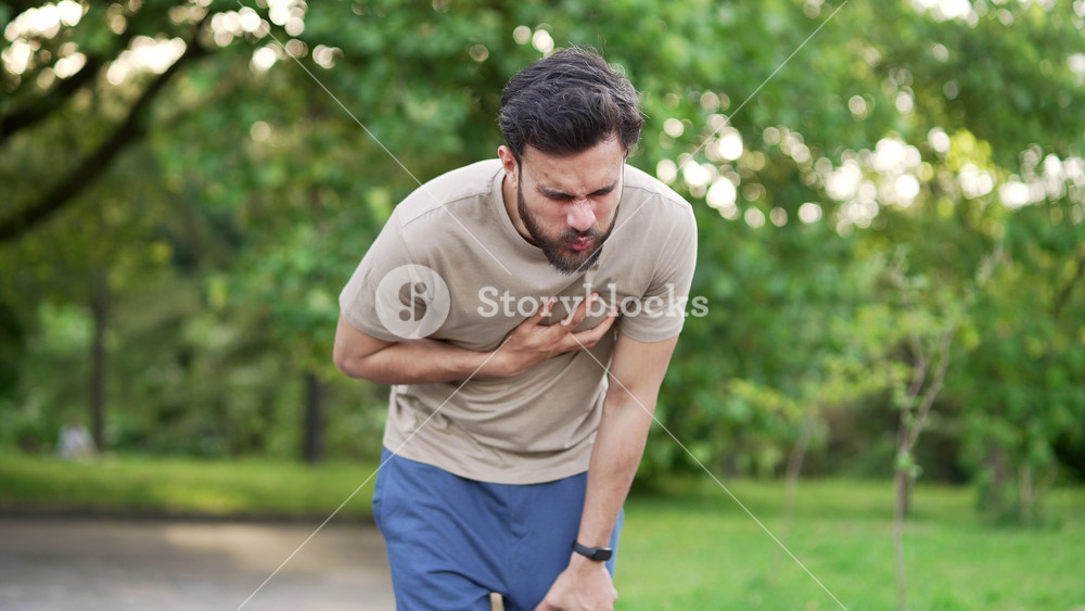 Sportsman suffered a heart attack or chest pain during a run in park. He clutches his chest in pain and massages it with his hand. Tired athlete suffers from tension in the heart. Health care concept