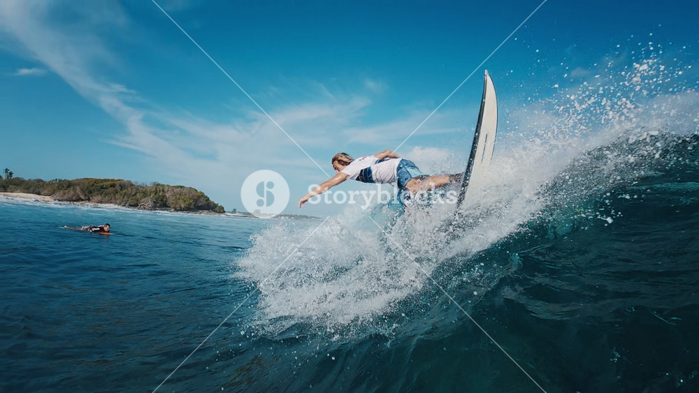Teen boy surfer rides the ocean wave and does radical turns on the wave in the Maldives. In water and underwater view of the surfer on the wave