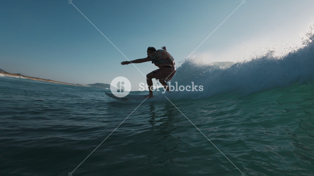 Stylish surfer. Young man in bright colorful shirt surfs the wave. Speed warp effect applied with frozen movement of the rider