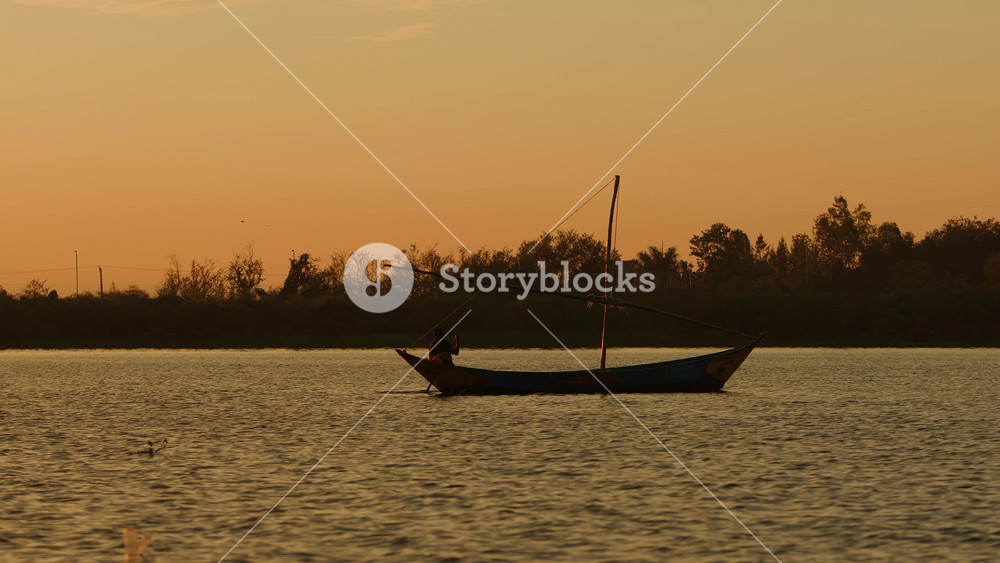 Kisumu, Kenya - June 6, 2025: African man paddles boat with structure made of sticks for sail during an evening fishing trip on lake