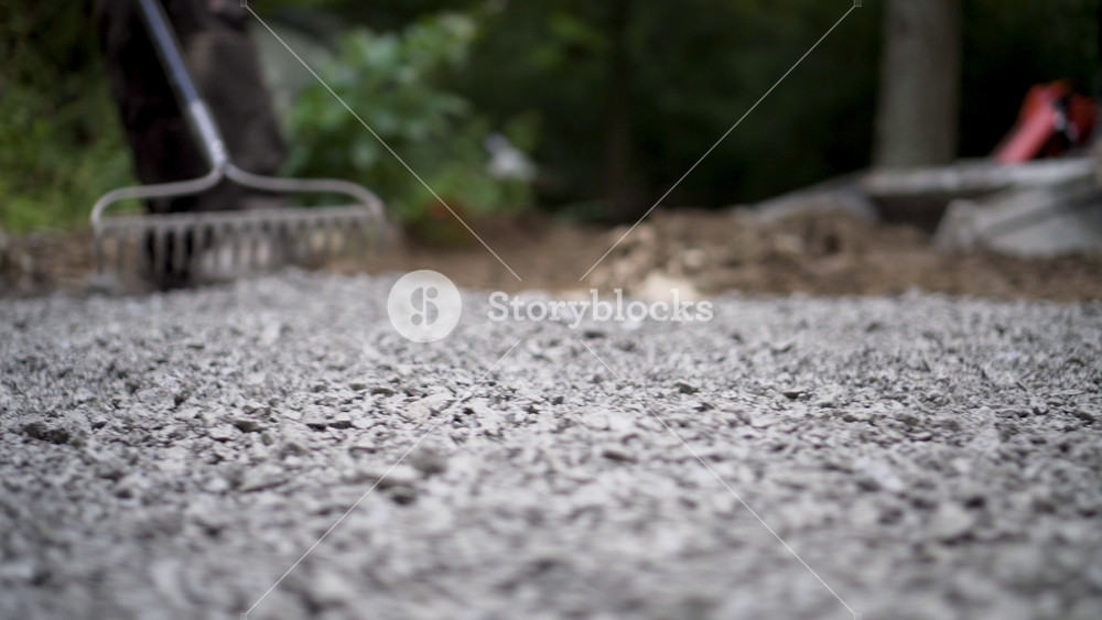 Closeup of a rake, raking the gravel into the areas to try and even it out at the start of the hardscaping process.