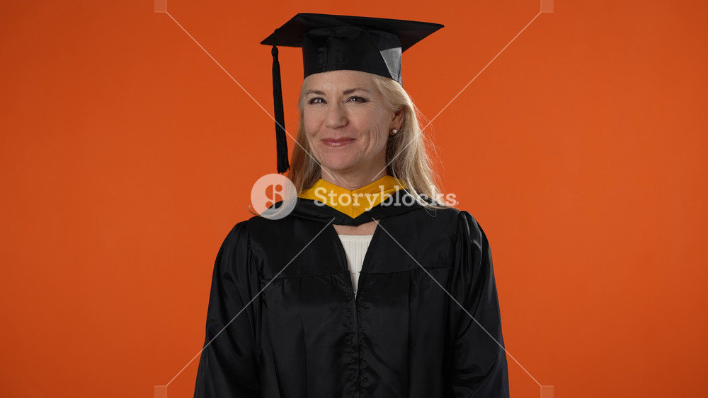 Portrait of happy senior graduate student woman in mortar board with diploma laughing over orange background graduation, education and old people concept