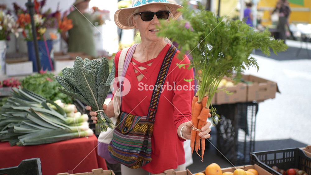 Mature woman smiles while selecting vegetables and fruits at the market in Sonoma California, enjoying a sunny morning outdoors