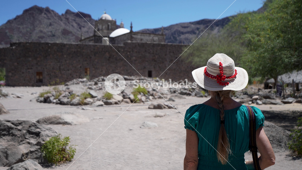 Mature woman enjoys her time visiting the grounds around the historic San Javier Mission near Loreto in the desert oasis of Baja California