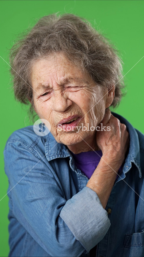 Vertical video portrait of elderly mature old woman with health problem neck pain, with wrinkled skin and grey hair on green screen background.