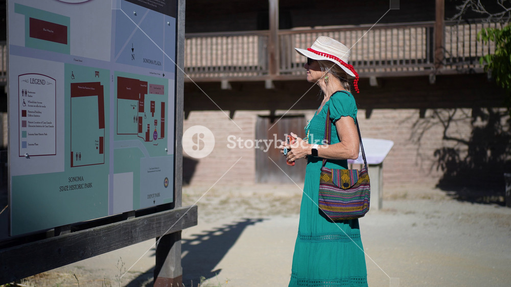 Happy senior woman reads about the history of Casa Grande while walking outside in Sonoma, California just after sunrise