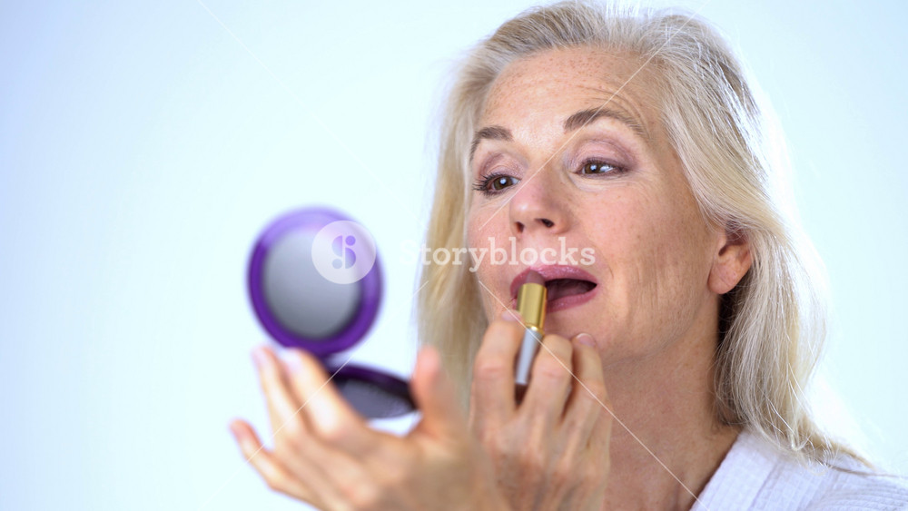 Mature middle-aged elderly woman model makeup hygienic lipstick applying moisturizing lip balsam natural beauty face skin care anti-aging cosmetic flirty senior lady smiling on white studio background