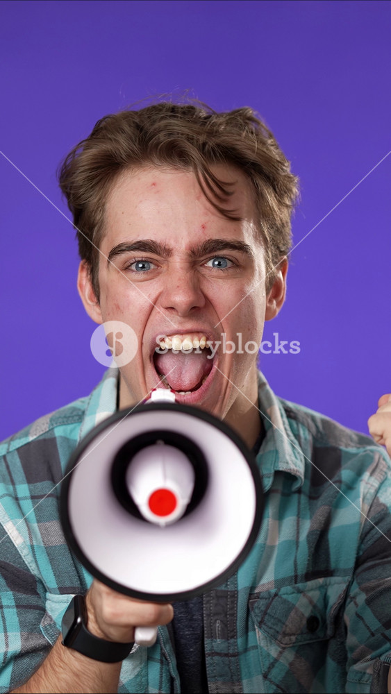 Vertical video portrait front view of excited young man 20s years old in casual shirt isolated on purple background studio. People lifestyle concept. Screaming in megaphone looking at camera