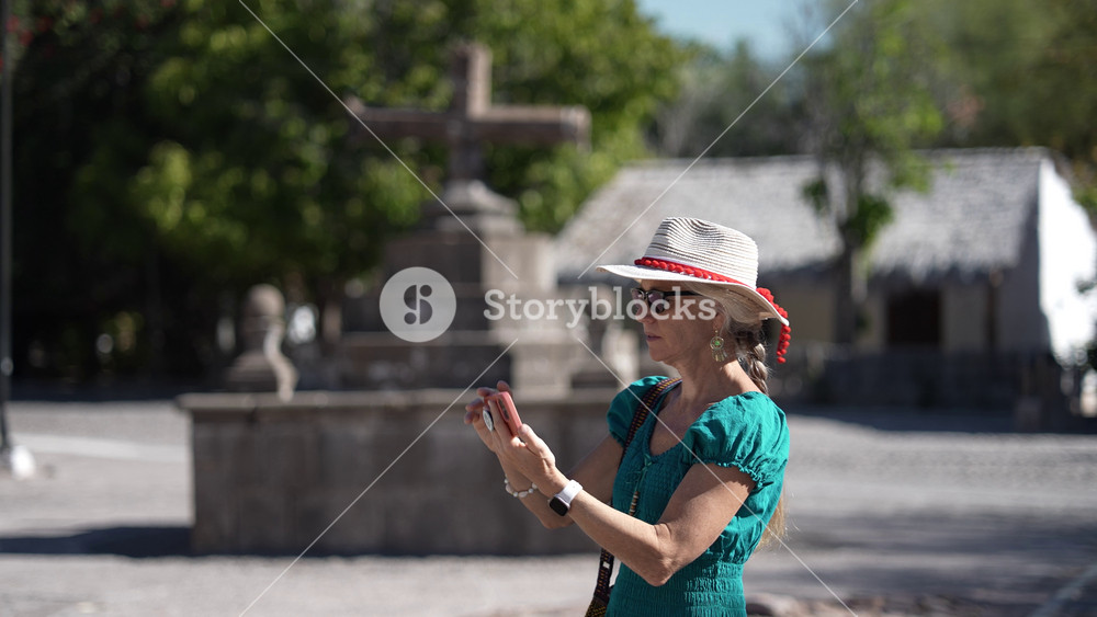 Mature woman captures images with her phone at San Javier Mission near Loreto in Baja California Sur at sunrise in the desert