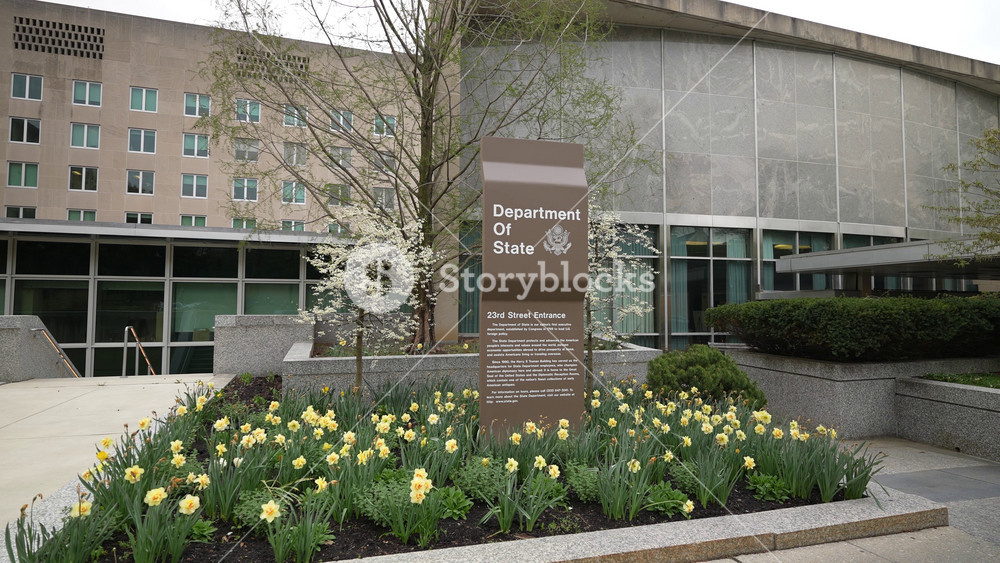Static view of corner of Harry S Truman Department of State building in Washington, DC on an overcast day with tulips in bloom.