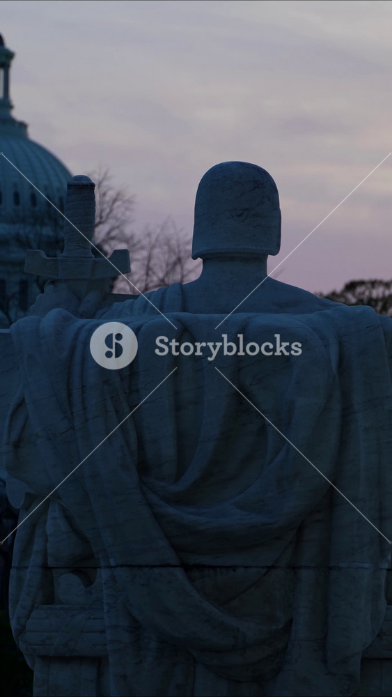 Vertical video view pushing in to the back of the Authority of Justice sculpture looking towards the US Capitol from the of the US Supreme Court building.