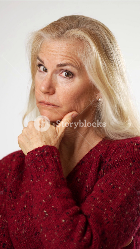 Vertical video portrait of mature woman say hush be quiet with finger on lips shhh gesture red sweater posing isolated on white background in studio. People sincere emotions, lifestyle concept.