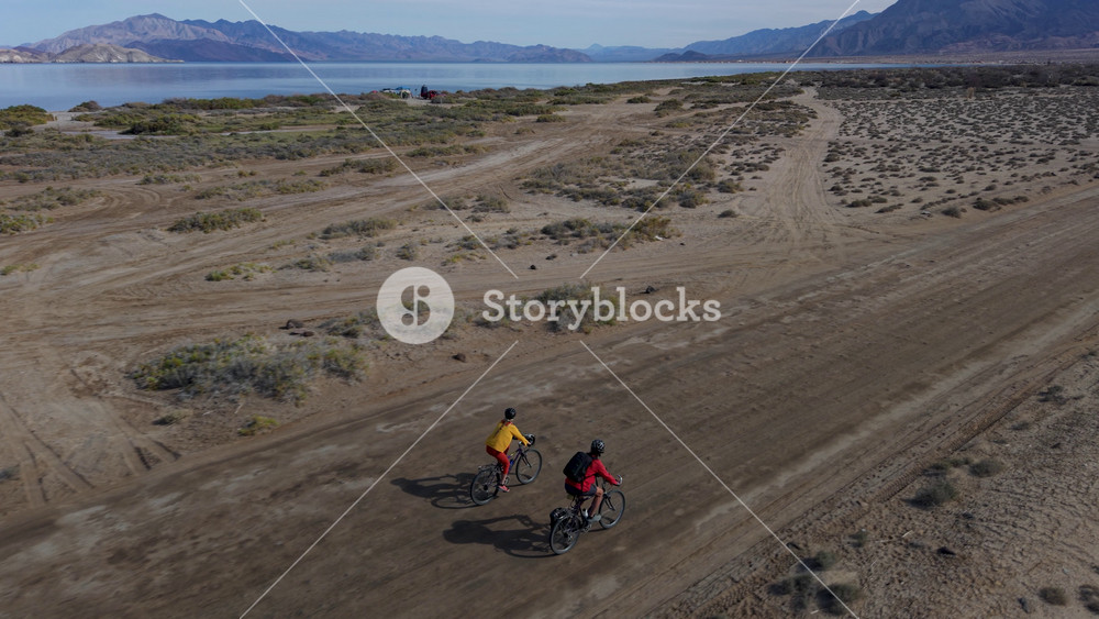 A mature man and woman bike in Mexico along the coast near La Gringa, enjoying the view of the Bahia De Los Angeles and the desert landscape