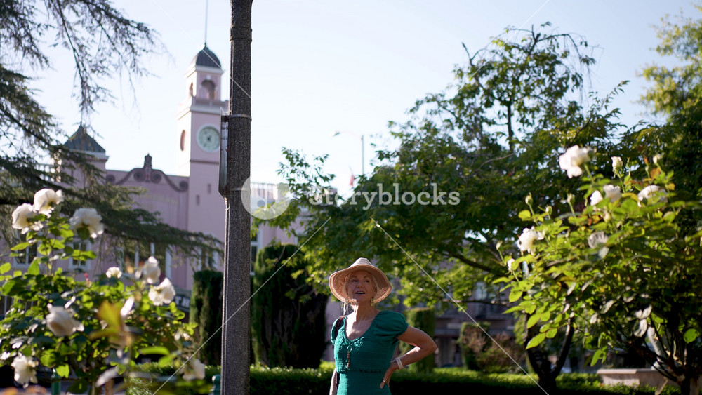 A woman walks happily by the Sebastiani Theater in Sonoma California, enjoying the flowers and beauty of the sunny morning