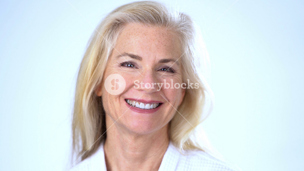 Closeup portrait of happy attractive mature woman wearing bathrobe smiling looking at camera. Advertising of body care spa concept.