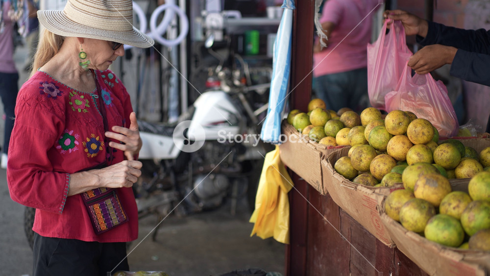 Mature woman shops at the street market in Granada Nicaragua, selecting fresh fruits and enjoying the local atmosphere and culture