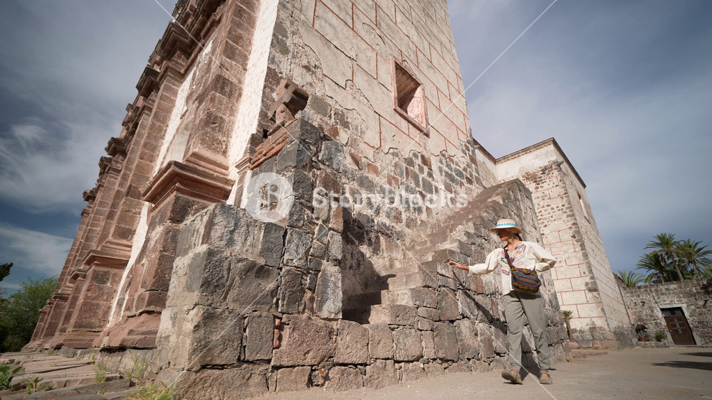 Mature woman takes in the sights of Mission Church in San Ignacio, Baja California Sur, while experiencing the local culture and history