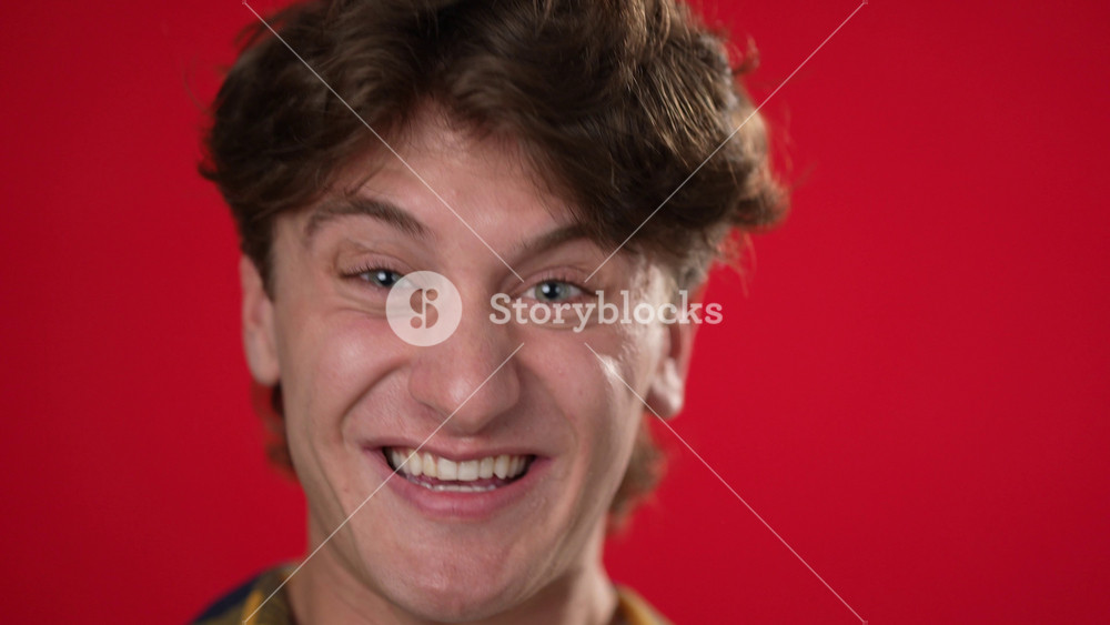 Slow motion extreme closeup portrait of face of happy young man 20s anticipate great success, WOW, winner, isolated on red background.