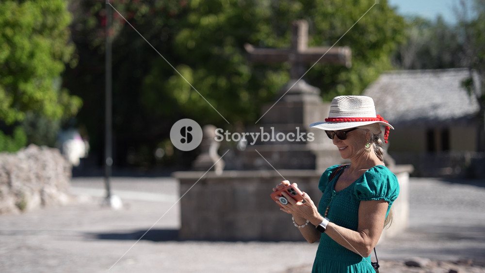 Senior woman takes photos at the entrance of San Javier Mission while the sun rises in Baja California Sur, Mexico