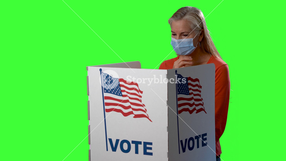 Conceptual green screen of mature woman medical face mask in voting booth at ballot box, careful decision for presidency, congress, senate in US election during pandemic.