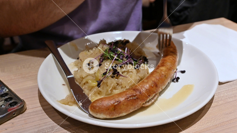 Munich, germany, december 27, 2025. Delicious traditional german meal of bratwurst and sauerkraut being eaten with a knife and fork. A classic european cuisine dish for dinner